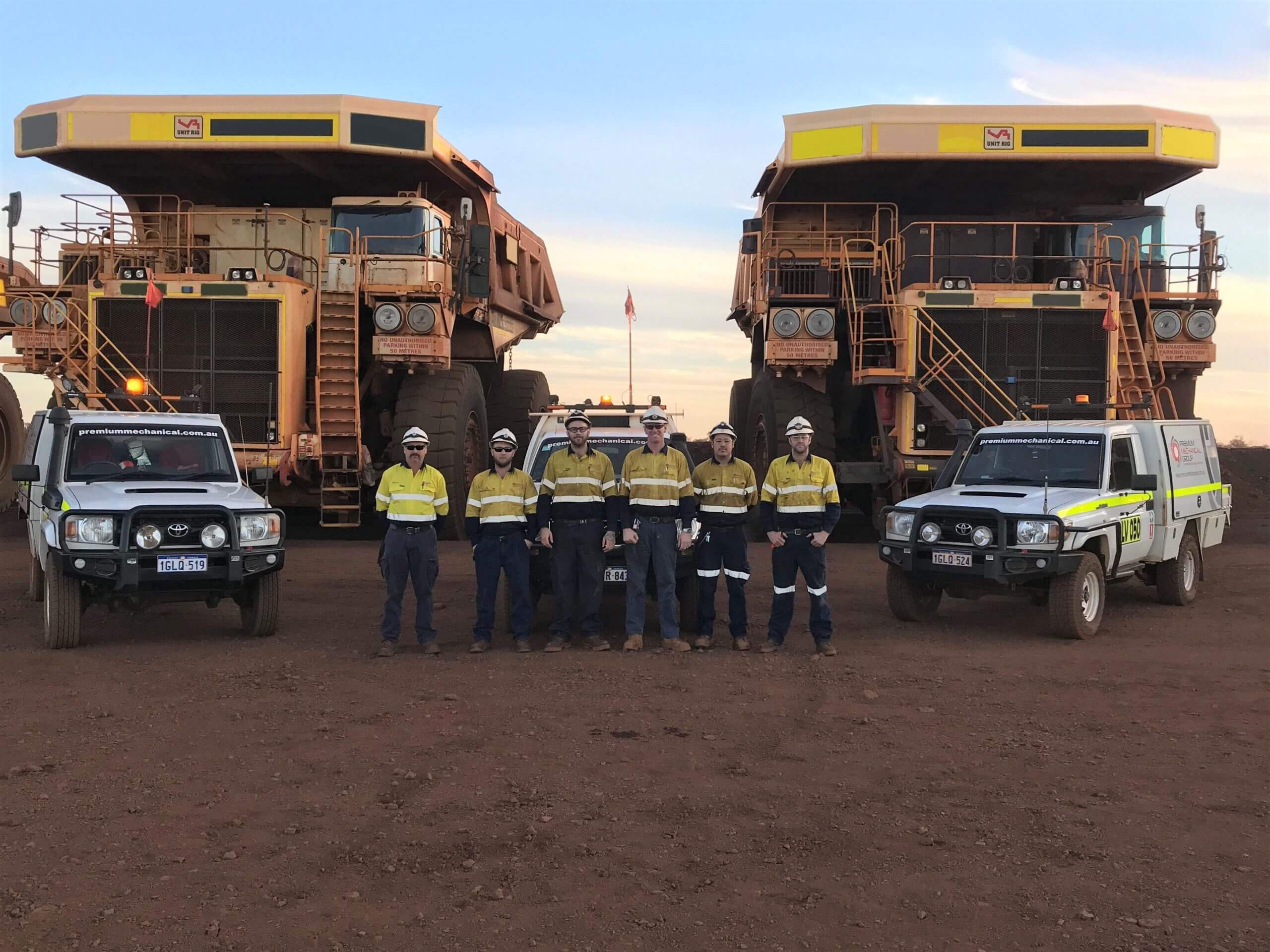 FIFO workers standing in front of diesel mining trucks.