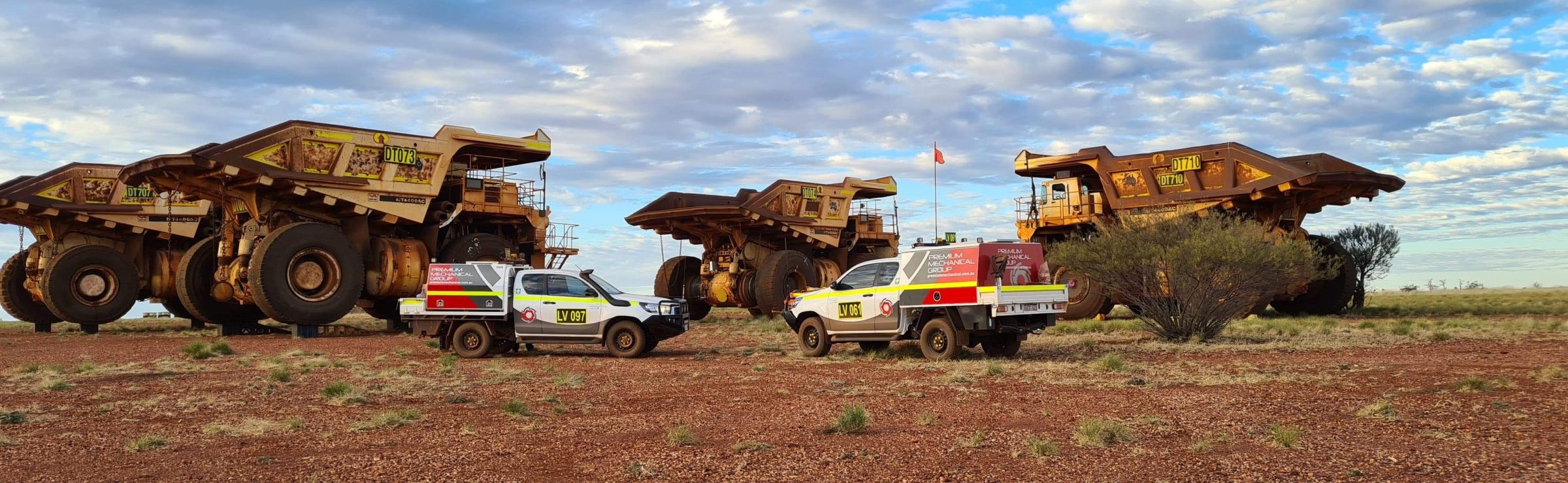 Three large trucks and a bulldozer with large tires, seen in a mining site.